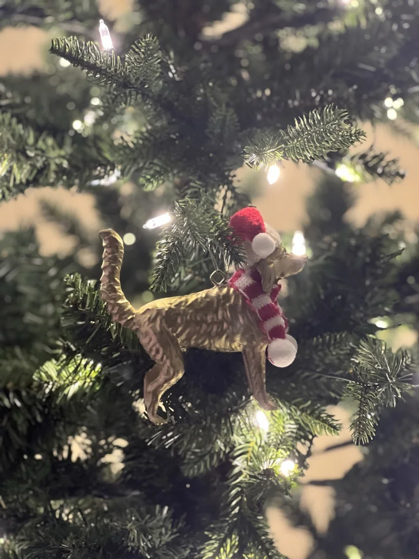 A gold English Setter ornament hanging on a lit tree.